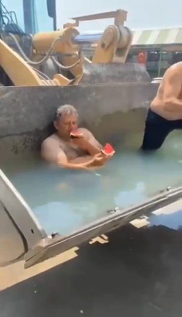 İznik'te sıcaktan bunalan inşaat işçileri, kepçenin küreğini havuza çevirdi. Suyun